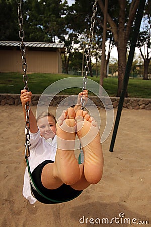 Girl with her feet together in the air swinging Stock Photo