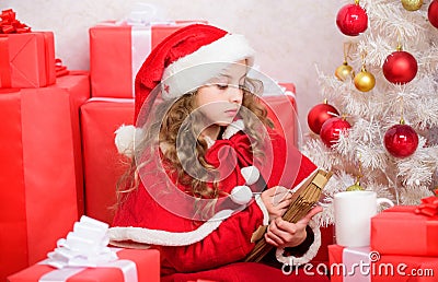 Girl hold pen and paper near christmas tree and gift box. Believe in miracle. Send letter for santa. Wish list. Child Stock Photo