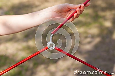 The girl is holding an arc from the tent. Close up detail of camping tent. Aluminum tent poles. Process of installing tent, settin Stock Photo