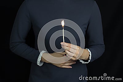 Girl holding a burning match against the background of the stomach, burning in the stomach, heartburn, black background Stock Photo