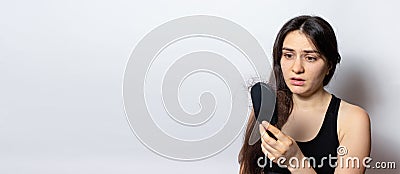 The girl is holding a hairbrush with lost hair. Hair loss, care and treatment. Trichologist, trichology. Banner with Stock Photo
