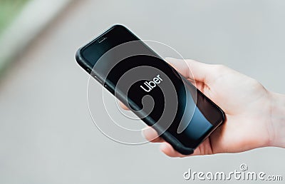 Girl holding iPhone showing Uber app on screen. Editorial Stock Photo