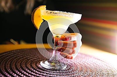 Girl holding margarita cocktail on the table in the restaurant. Alcoholic drinks. Beautiful hands Stock Photo