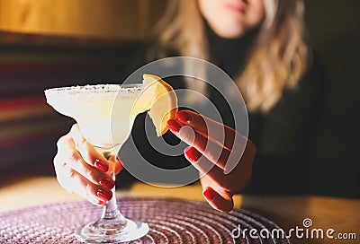 Girl holding margarita cocktail on the table in the restaurant. Alcoholic drinks. Beautiful hands Stock Photo