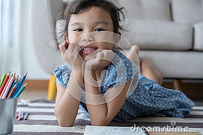 The girl holding a pencil and smiling, This one asian little girl is playing in the living room at home .she smile very happily Stock Photo