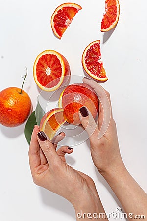 The girl is holding a slice of orange. Sliced oranges on a white table. Top view Stock Photo