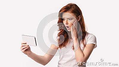Girl Holding Smartphone Reading Shocking News Online, White Background Stock Photo