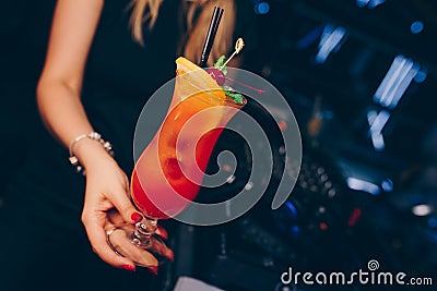 Girl holding Sweet Famous juicy red with orange Author inspired Cocktail Drink -on bar counter . Female Close-up Top view . Copy Stock Photo
