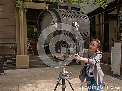 The girl is holding on to a large movie projector with her hands Stock Photo