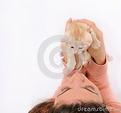 Girl holding up adorable orange little cat, happy animal concept Stock Photo