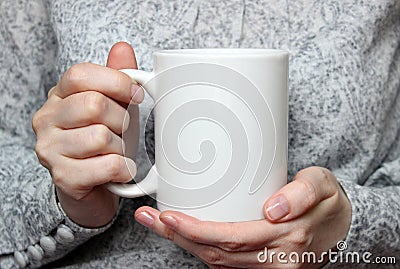 Girl is holding white cup in hands. White mug in woman's hands. Stock Photo