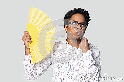 Girl holding yellow fan saves from unbearable heat fanning herself Stock Photo