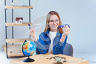 Girl holds airplane and car models in hands and choosing best transportation for trip.Travel around the world for your Stock Photo