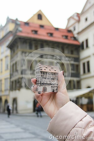 Girl holds czech souvenir house Minute House, Dum u Minuty, on background of that real house, Old Town Square Stock Photo