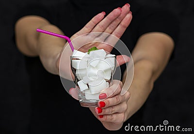 Girl holds a glass filled with cubes of white sugar, rejects the use of sugar Stock Photo