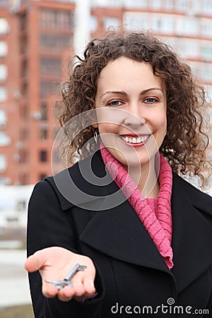 Girl holds key on palm against many-storeyed house Stock Photo
