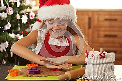 Girl in holidays mood making gingerbread cookies - cutting dough Stock Photo