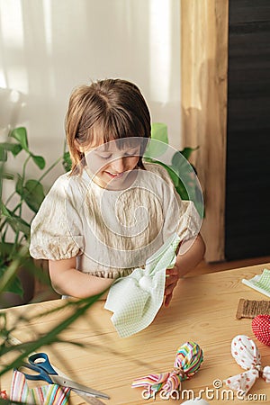 A girl at home prepares fabric for making Easter textile eggs in the shape of a hare with ears. Preparations for the Stock Photo