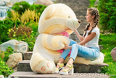 girl with a huge gift - a teddy bear in the park Stock Photo