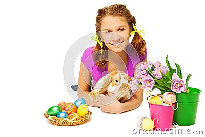 Girl hugging rabbit with Eastern eggs on floor Stock Photo