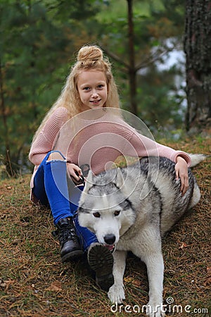 A girl with a husky walks in the forest. Stock Photo