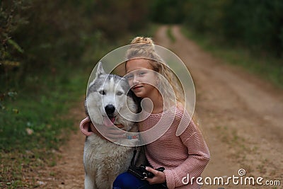 A girl with a husky walks in the forest. Stock Photo