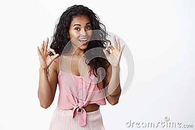 Girl impressed with good work. Attractive african-american female with curly hairstyle, showing okay, excellent gesture Stock Photo