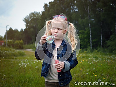 Girl inflates soap bubble. Portrait of a child. Stock Photo