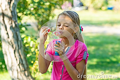 Girl inflates soap bubbles on a bright sunny day in the park Stock Photo