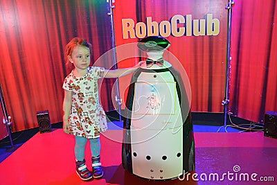 A girl at the interactive robot exhibition Robostars plays with a robot. Editorial Stock Photo