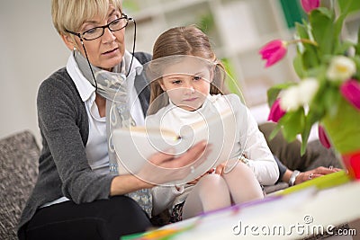 Girl interested looks at the book while grandma read Stock Photo