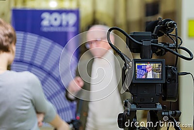 The girl interviews the man. Video shooting in the interior. LCD display on the camcorder Editorial Stock Photo