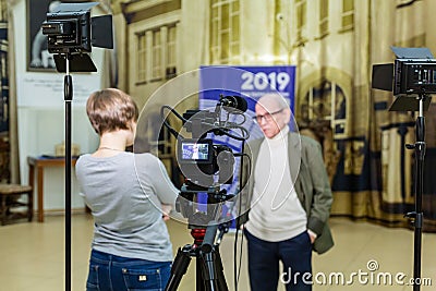 The girl interviews the man. Video shooting in the interior. LCD display on the camcorder Editorial Stock Photo