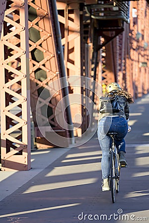 Girl in jeans and backpack riding bike over the bridge Editorial Stock Photo