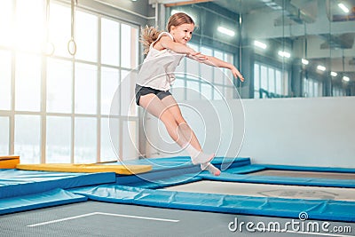 Girl jumping high in striped tights on trampoline. Stock Photo