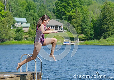 Girl jumping into lake off dock at cottage Stock Photo