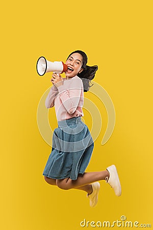 A girl jumping and screaming using a megaphone on Stock Photo