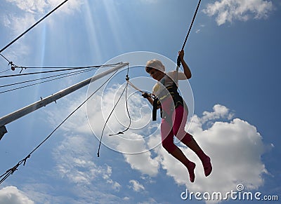 Girl jumping on a trampoline with ropes Stock Photo