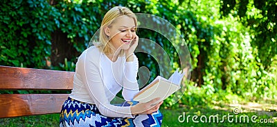 Girl keen on book keep reading. Reading literature as hobby. Girl sit bench relaxing with book, green nature background Stock Photo
