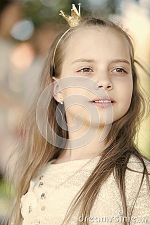 Girl kid on calm face with tiny golden crown on head, nature background, defocused. Girl princess with little crown Stock Photo