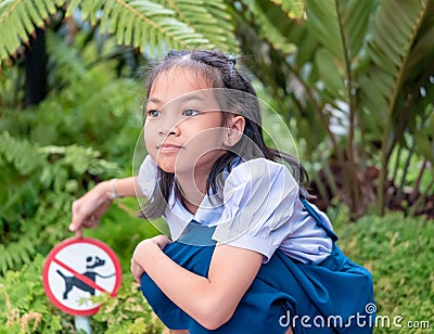 Girl kid pointing at no dog allow signage in a garden Stock Photo