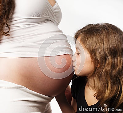 Girl kissing her moms pregnant tummy Stock Photo