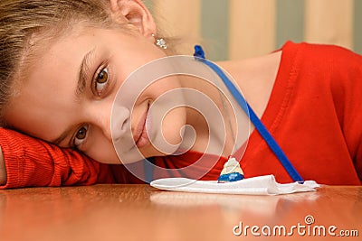 The girl laid her head on her hand and looked into the frame, painting dough figurines at the table Stock Photo