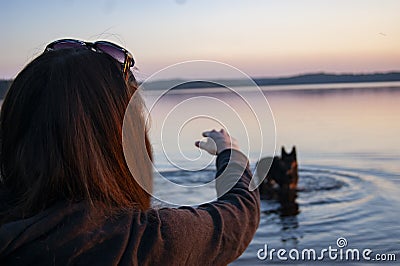 The girl on the lake playing with a dog Stock Photo