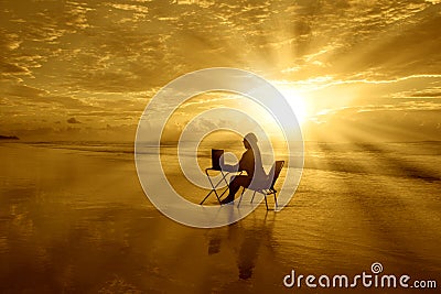 Girl-with-laptop-at-sunset-on-the-beach Stock Photo