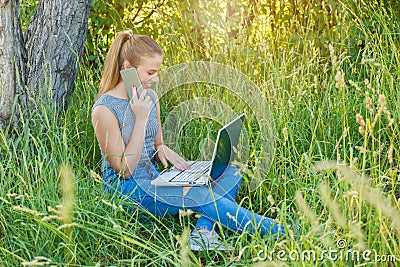 Girl with a laptop talking on the phone in nature Stock Photo