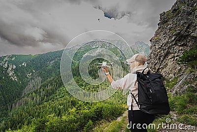 The girl launches a mini drone in the mountains in summer Stock Photo