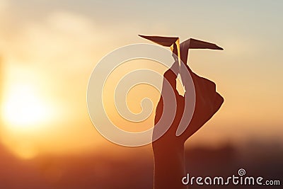 A girl is launching a paper airplane from a window at sunset. Support of the Telegram application and freedom internet. Stock Photo