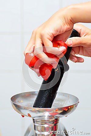 The girl lays down tomatoes in a juicer Stock Photo
