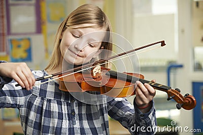 Girl Learning To Play Violin In School Music Lesson Stock Photo